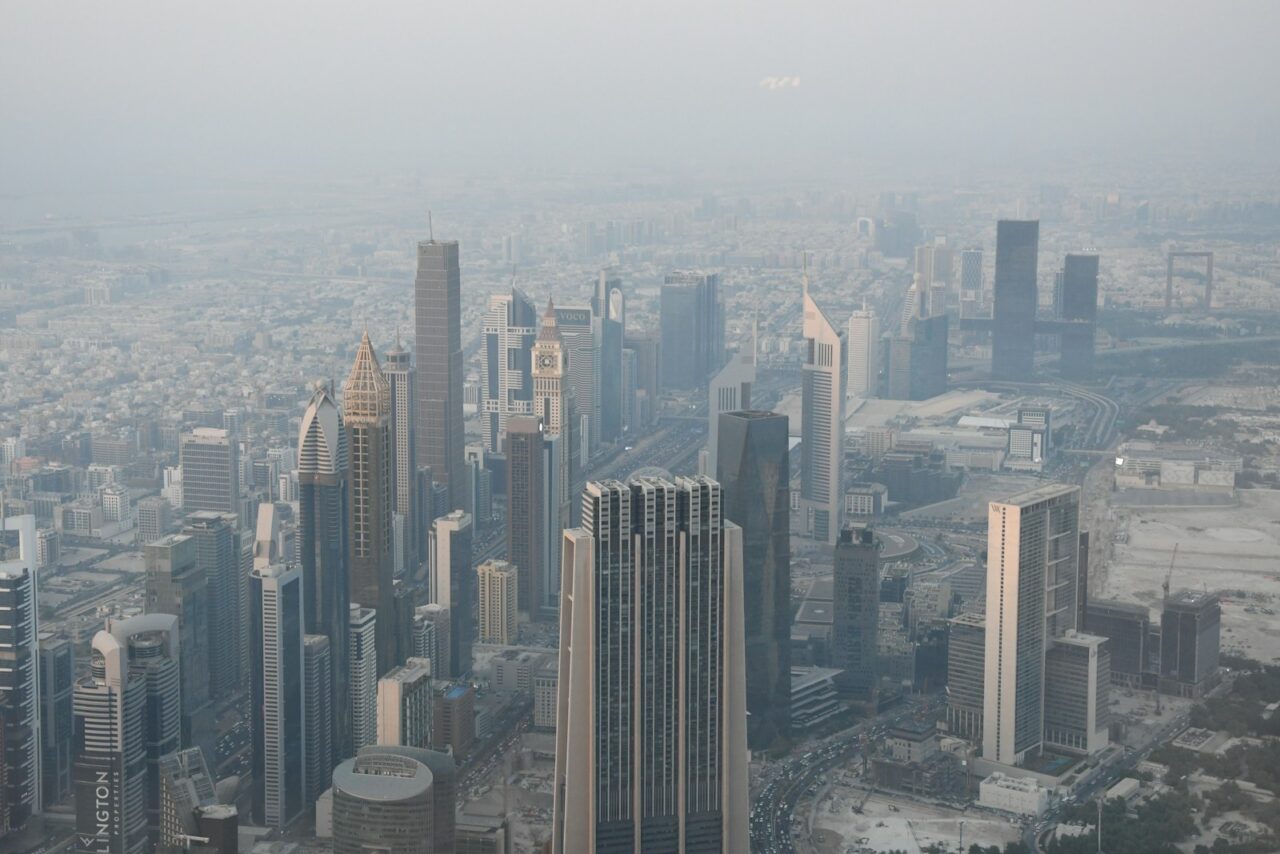 Aerial view of Dubai's high-rise towers and city grid under a hazy sky