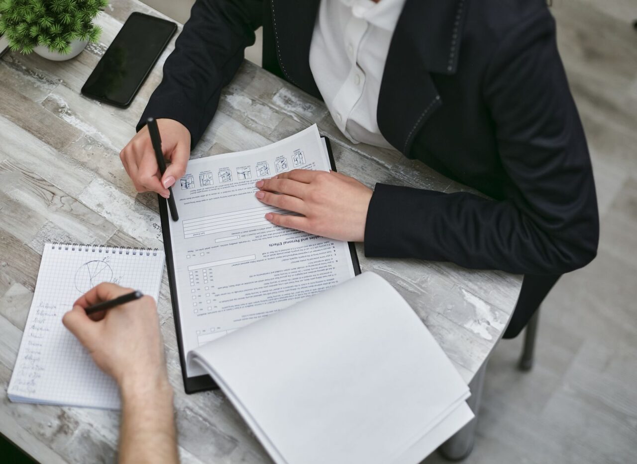 Two professionals reviewing a document on a clipboard and taking notes at a desk