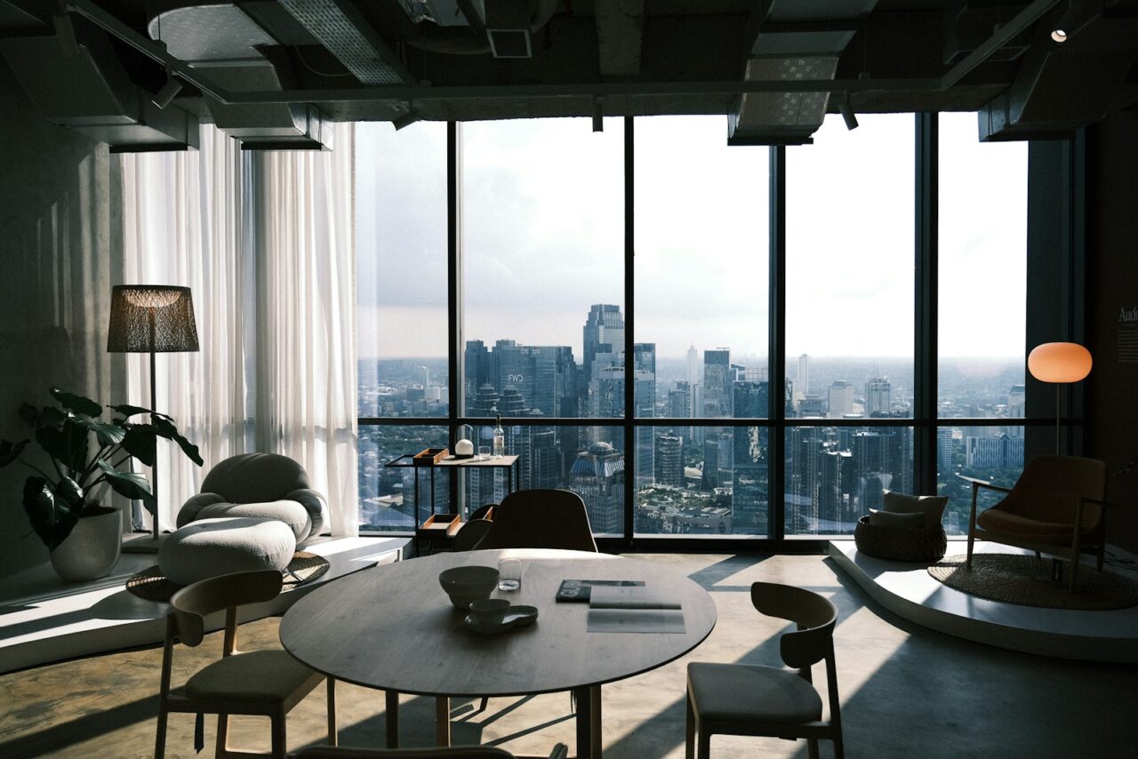 Newly furnished office with a round meeting table and floor-to-ceiling windows overlooking a city skyline