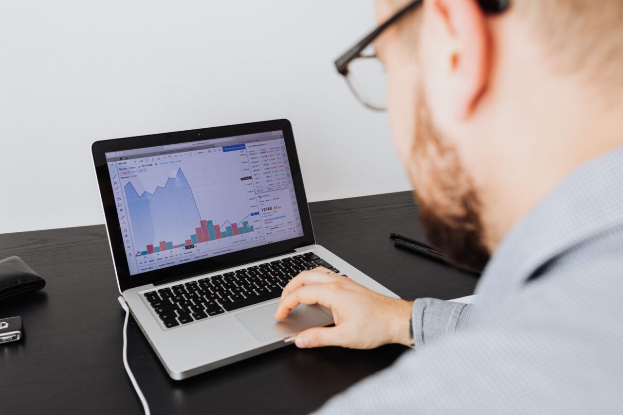 Business Valuation Services in Dubai — section1 Analyst in glasses reviewing area and bar charts on a laptop screen at a dark desk
