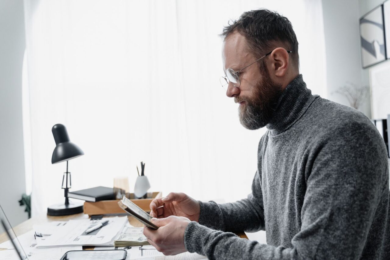 Business owner checking figures on a phone at a desk covered with invoices and receipts